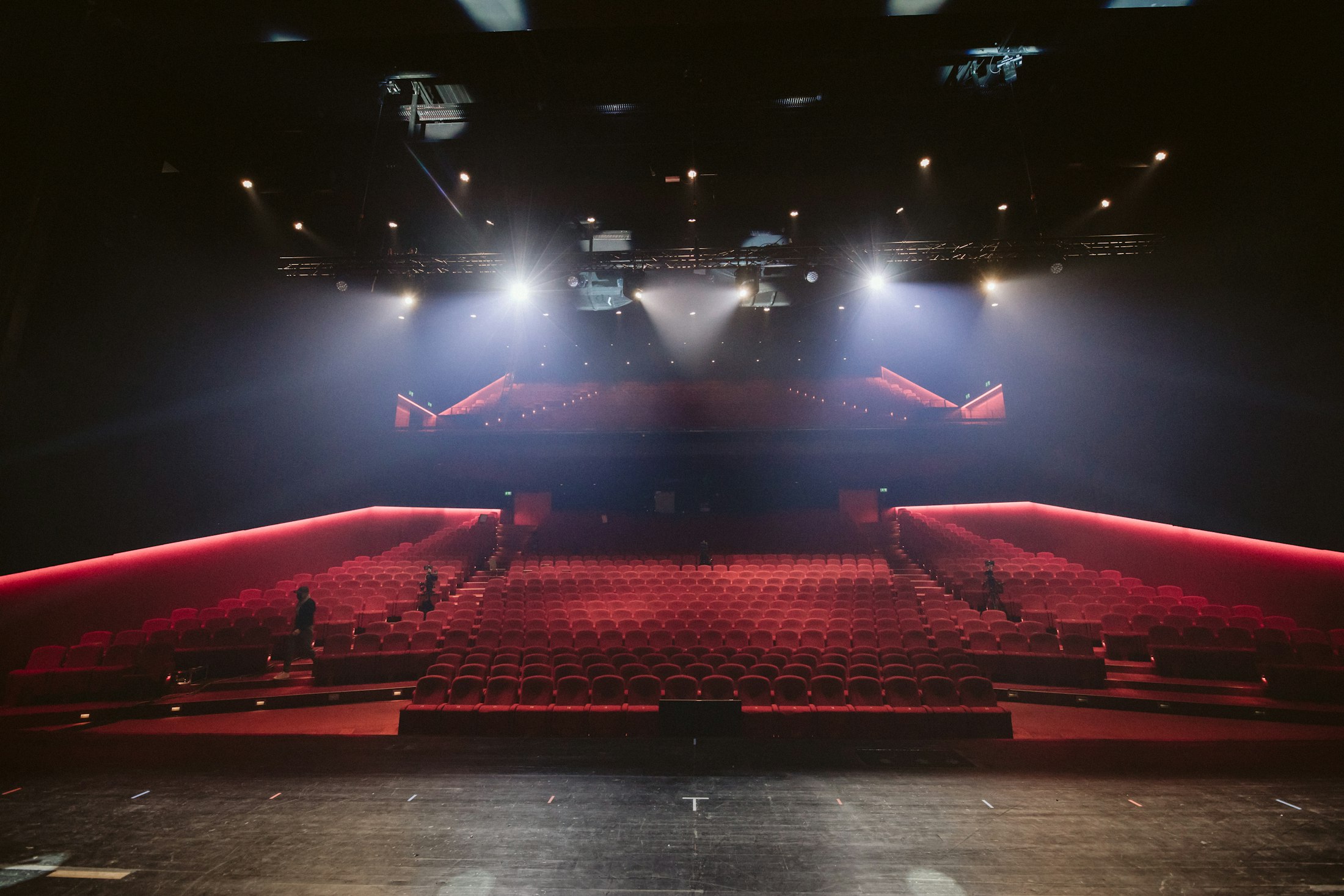 Auditorium stage lit by overhead spotlights, seen from the seating